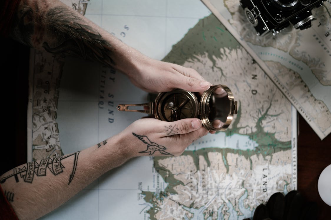 brújula vintage sobre mapa náutico con tatuajes marineros en las manos